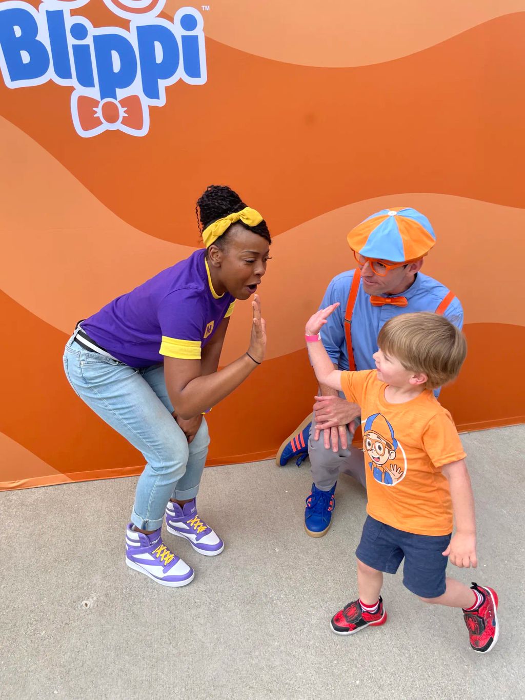 Blippi and Meekah high five with a fan