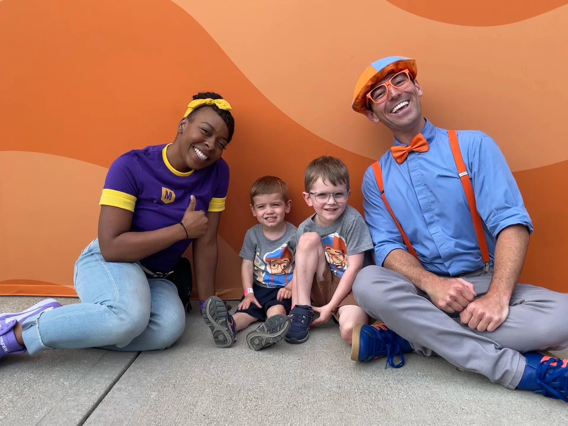 Blippi and Meekah kneeling down to 2 kids.